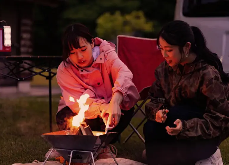 焚き火を囲んで笑顔で談笑する二人の女性