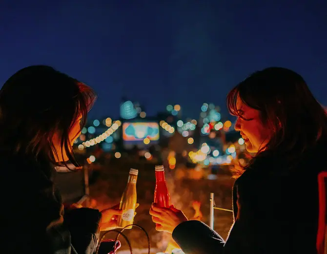 焚き火を囲んで楽しそうに笑う女性二人の参加者